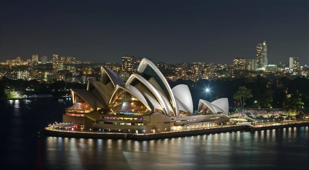 Night view of the Sydney Opera House with city lights reflecting on the harbor, symbolizing a welcoming destination for families considering a Parent Visa for Australia.