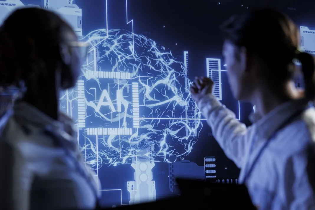 Two people are looking at a big digital screen showing a brain with the letters 