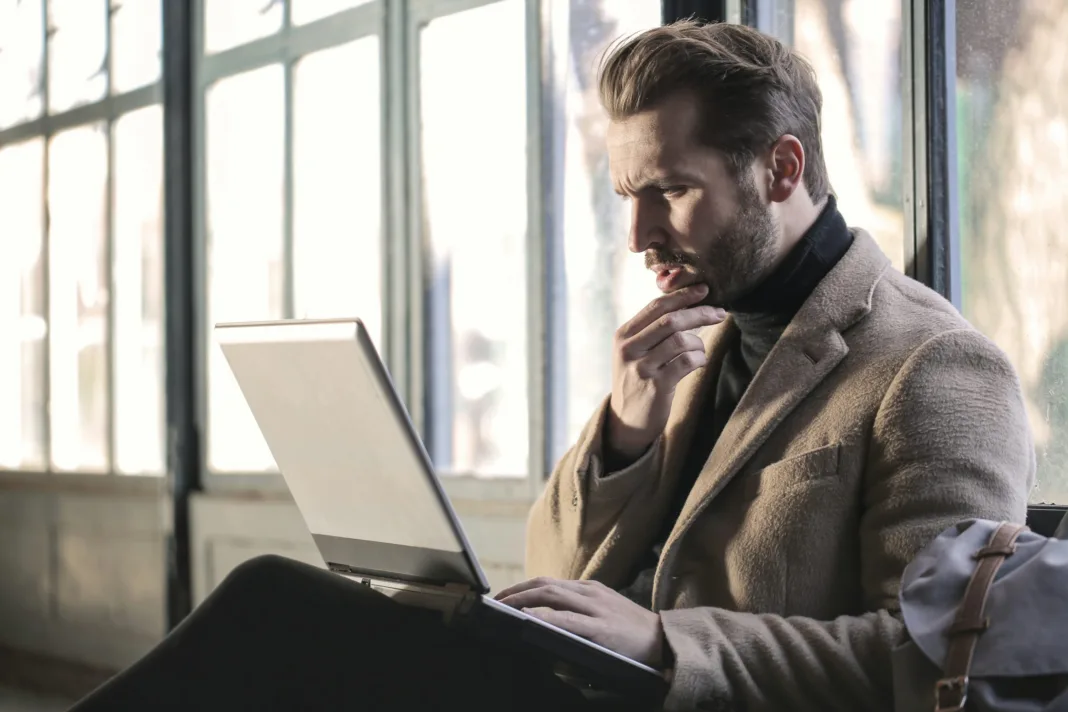 A man thoughtfully browsing the internet on his laptop, ensuring online privacy and security using a free VPN for pc service.